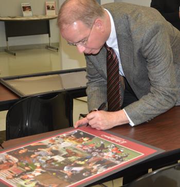 Dr. Michael V. Carter, president of Campbellsville University, signs one of the new Campbellsville University academic/athletic posters for U.S.  Congressman Ed Whitfield.  (Campbellsville University Photo by Joan C. McKinney)